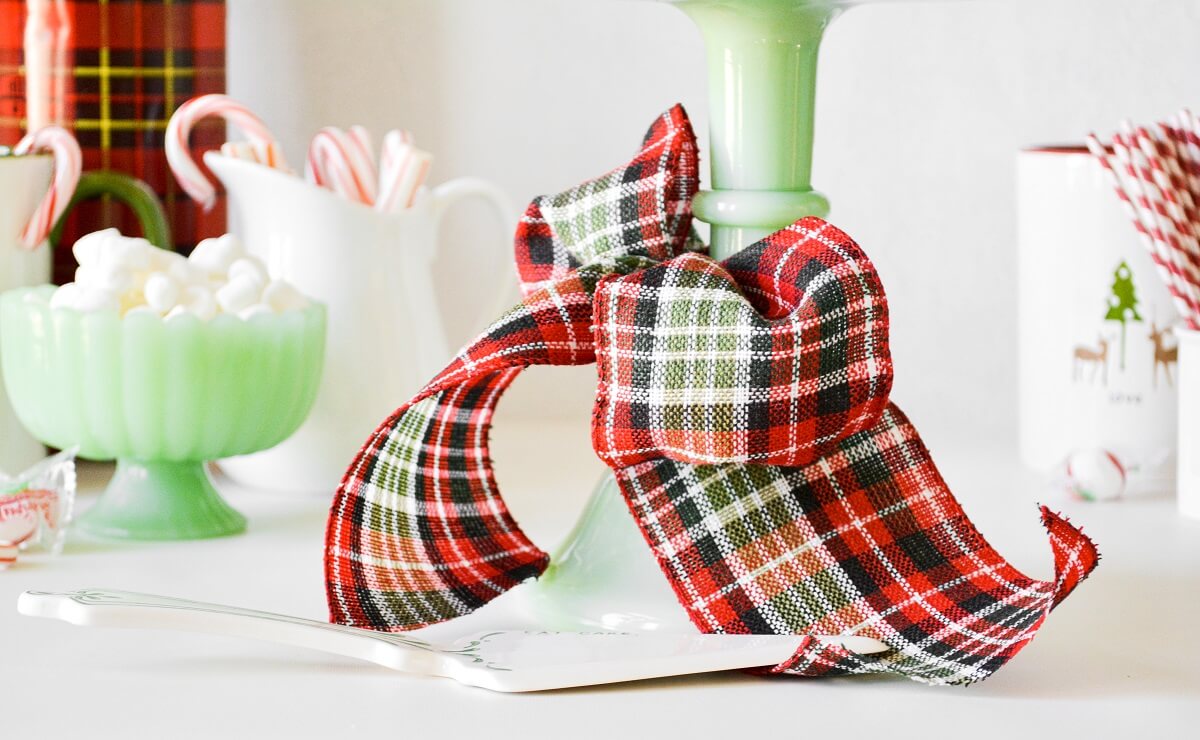 Red plaid bow tied around a green cake stand.