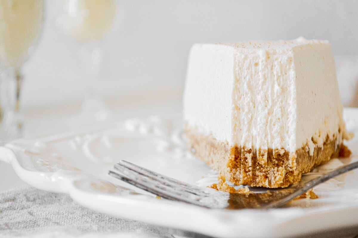 A piece of eggnog cheesecake with a bite taken.