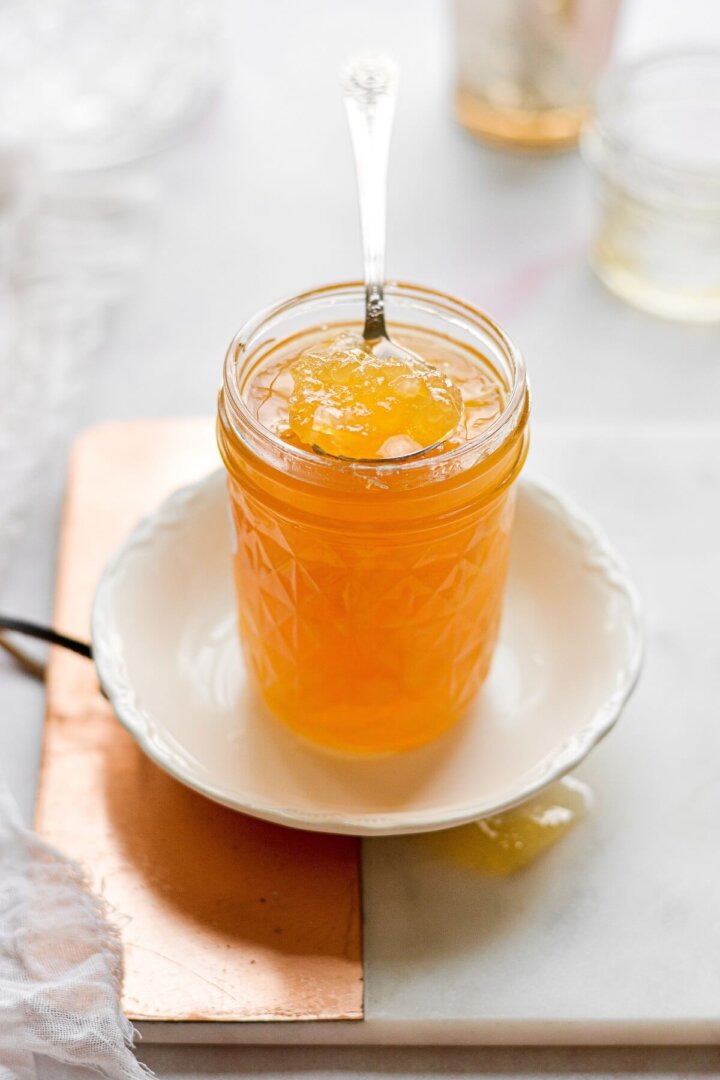 A jar of lemon marmalade with a silver spoon.
