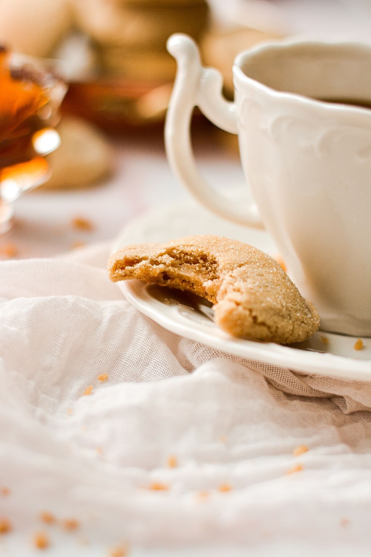 A half eaten soft maple cookie next to a cup of coffee.