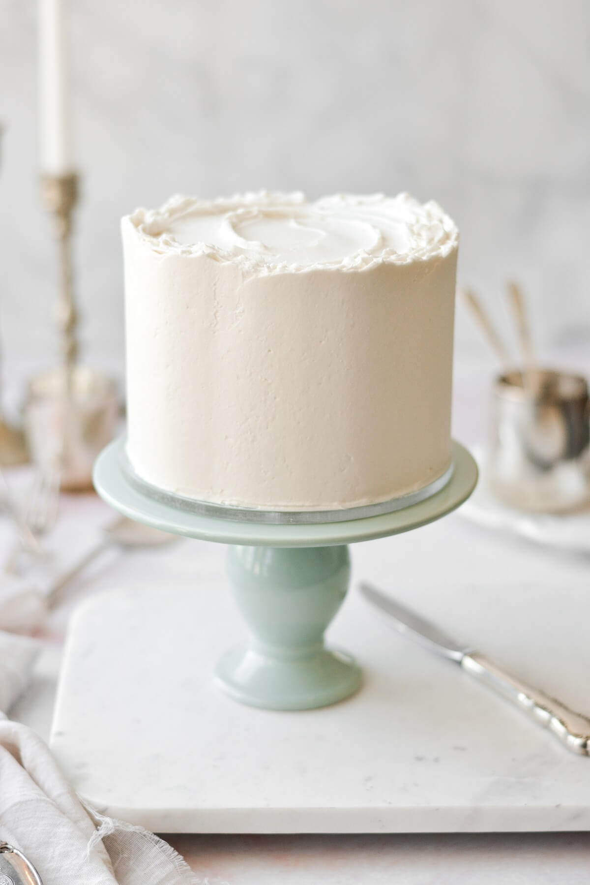 White velvet cake on a sage green cake stand.