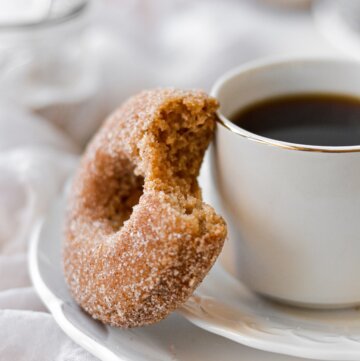 An apple cider doughnut next to a cup of coffee.