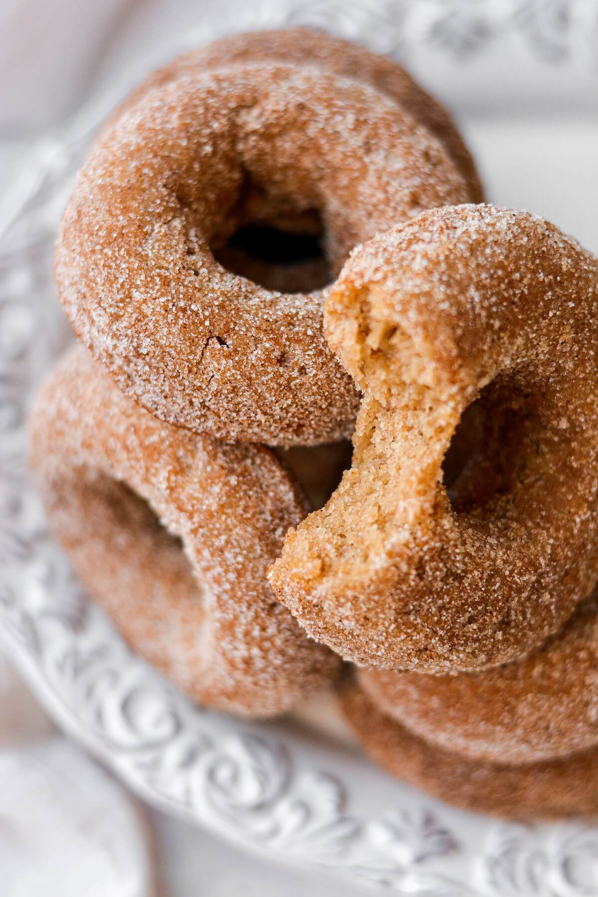 Apple cider doughnuts, one with a bite taken.