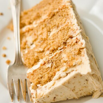 A slice of butter pecan cake on a white plate.