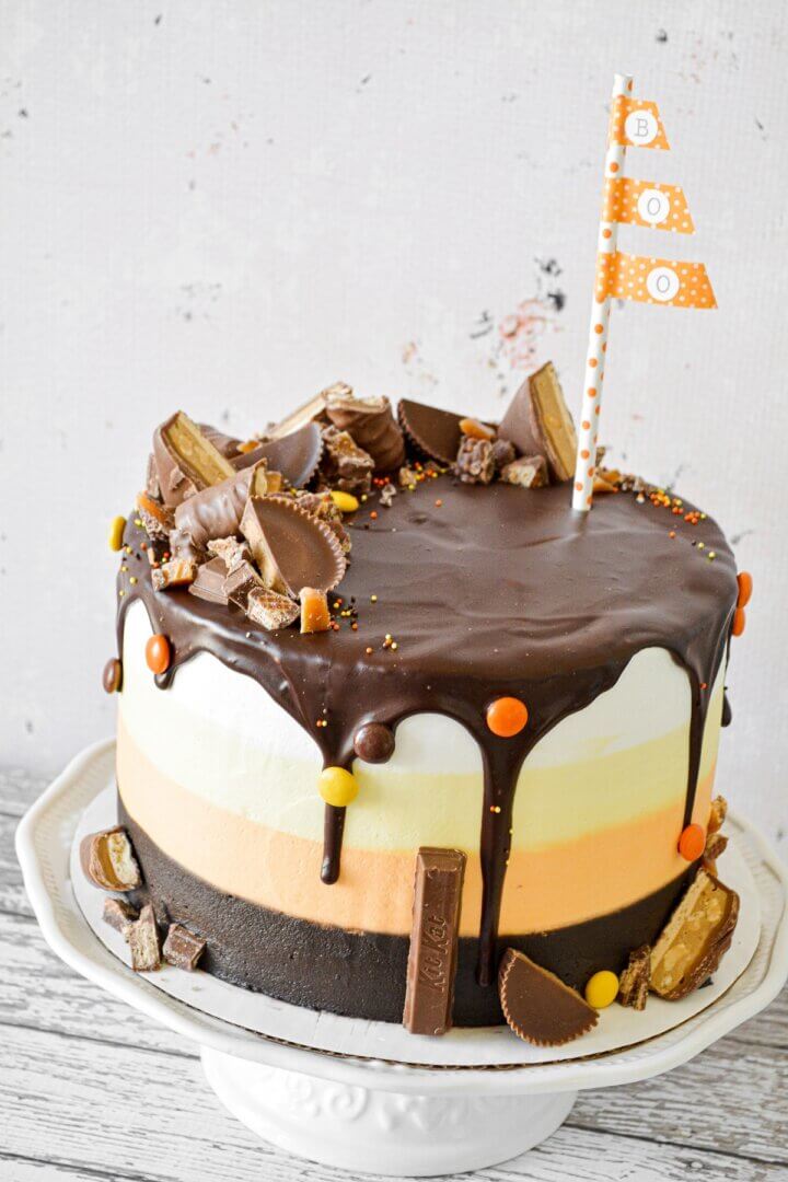 Halloween cake with striped layers of cake and buttercream in candy corn colors, decorated with candy.