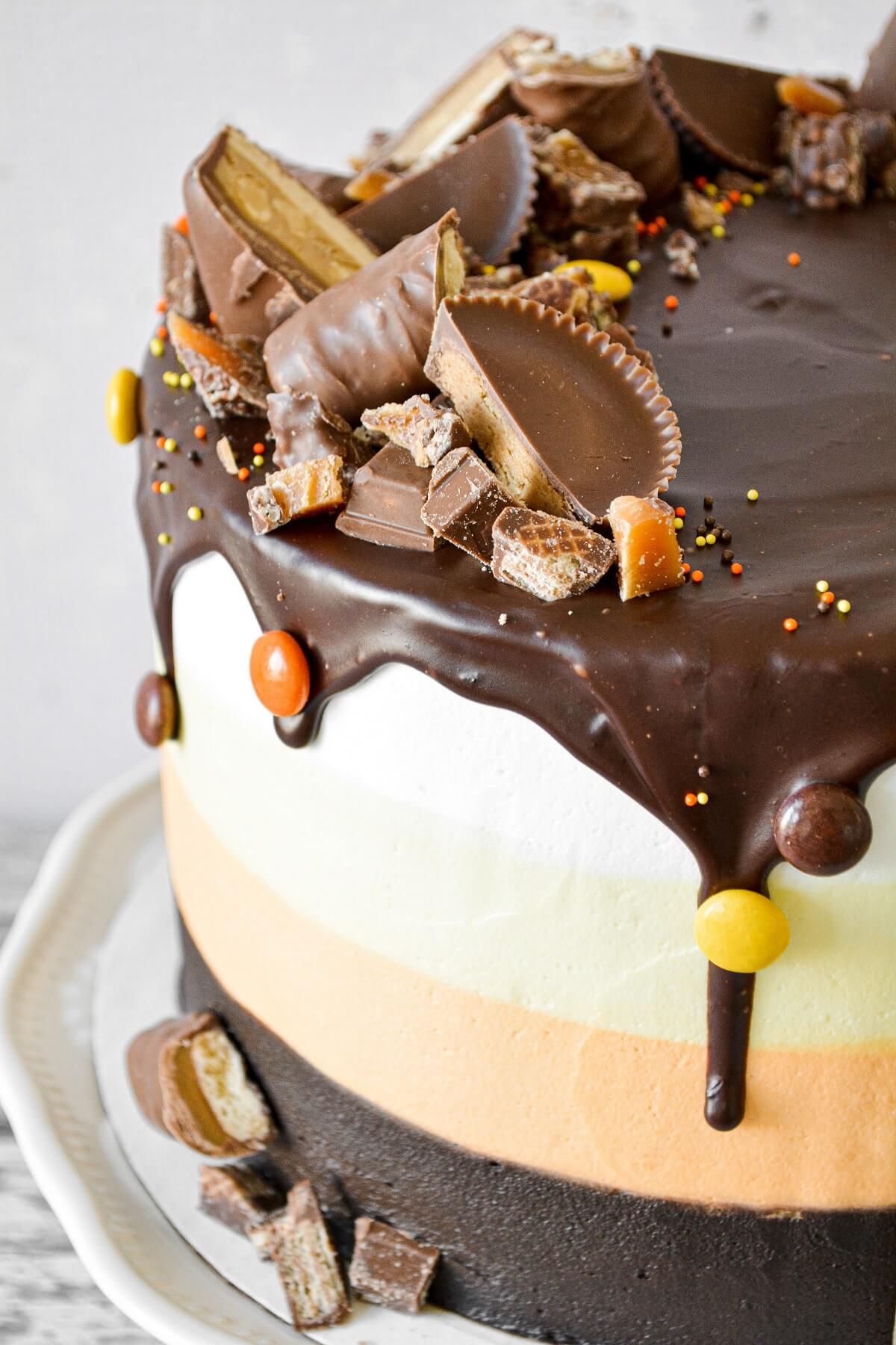 Halloween cake with striped layers of cake and buttercream in candy corn colors, decorated with candy.