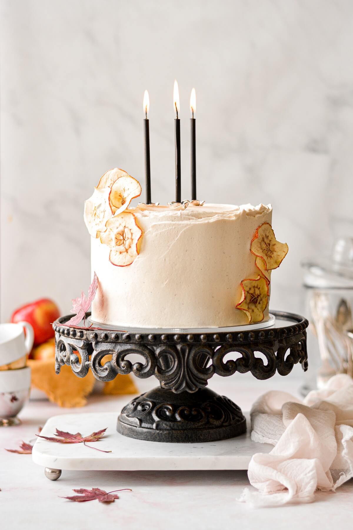 Apple cider cake with maple vanilla bean buttercream, with dried apples garnish and black candles.
