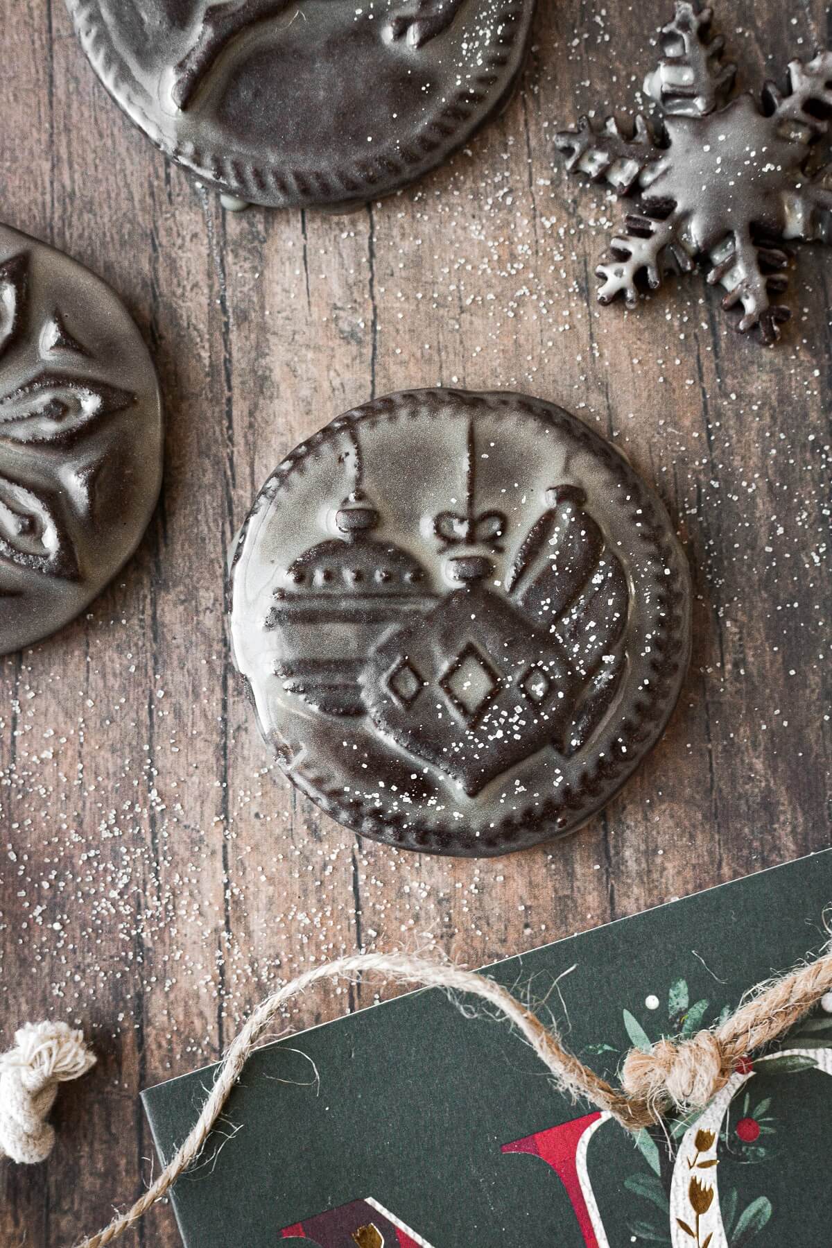 A chocolate Christmas cookie stamped with an ornament design and glazed in icing.