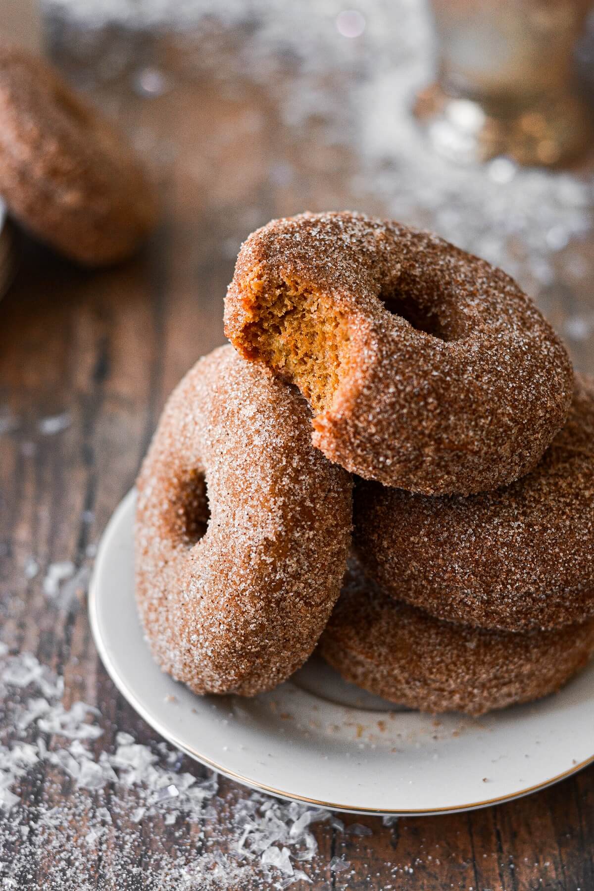 A stack of baked gingerbread doughnuts, one with a bite taken out of it.