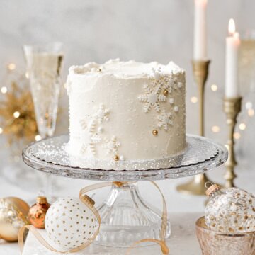 Champagne cake with snowflakes and sugar pearls, surrounded by Christmas ornaments.