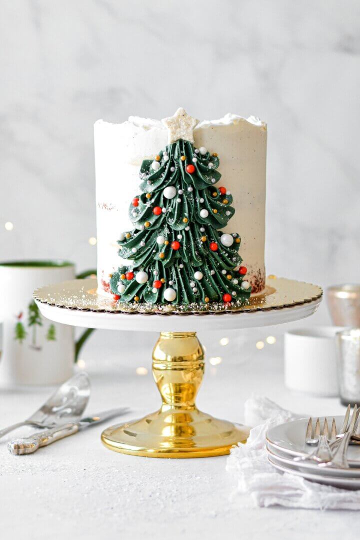 A Christmas tree cake with a buttercream Christmas tree decorated with sprinkle ornaments and a sugar star.