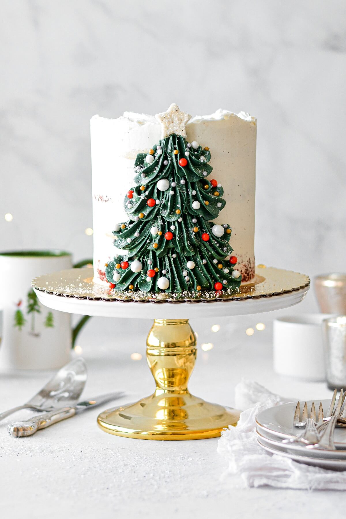 A Christmas tree cake with a buttercream Christmas tree decorated with sprinkle ornaments and a sugar star.