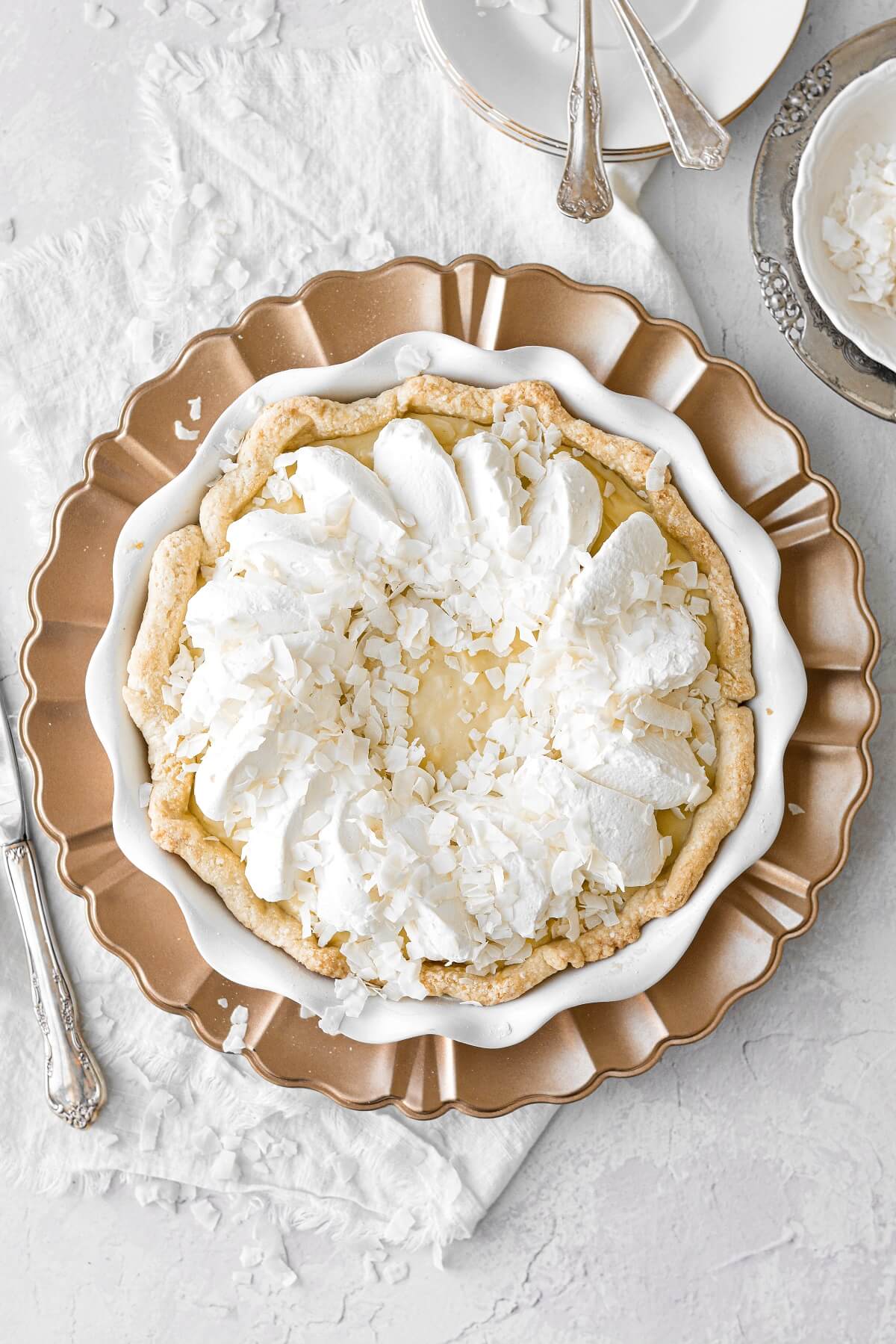 Coconut cream pie on a gold charger plate.