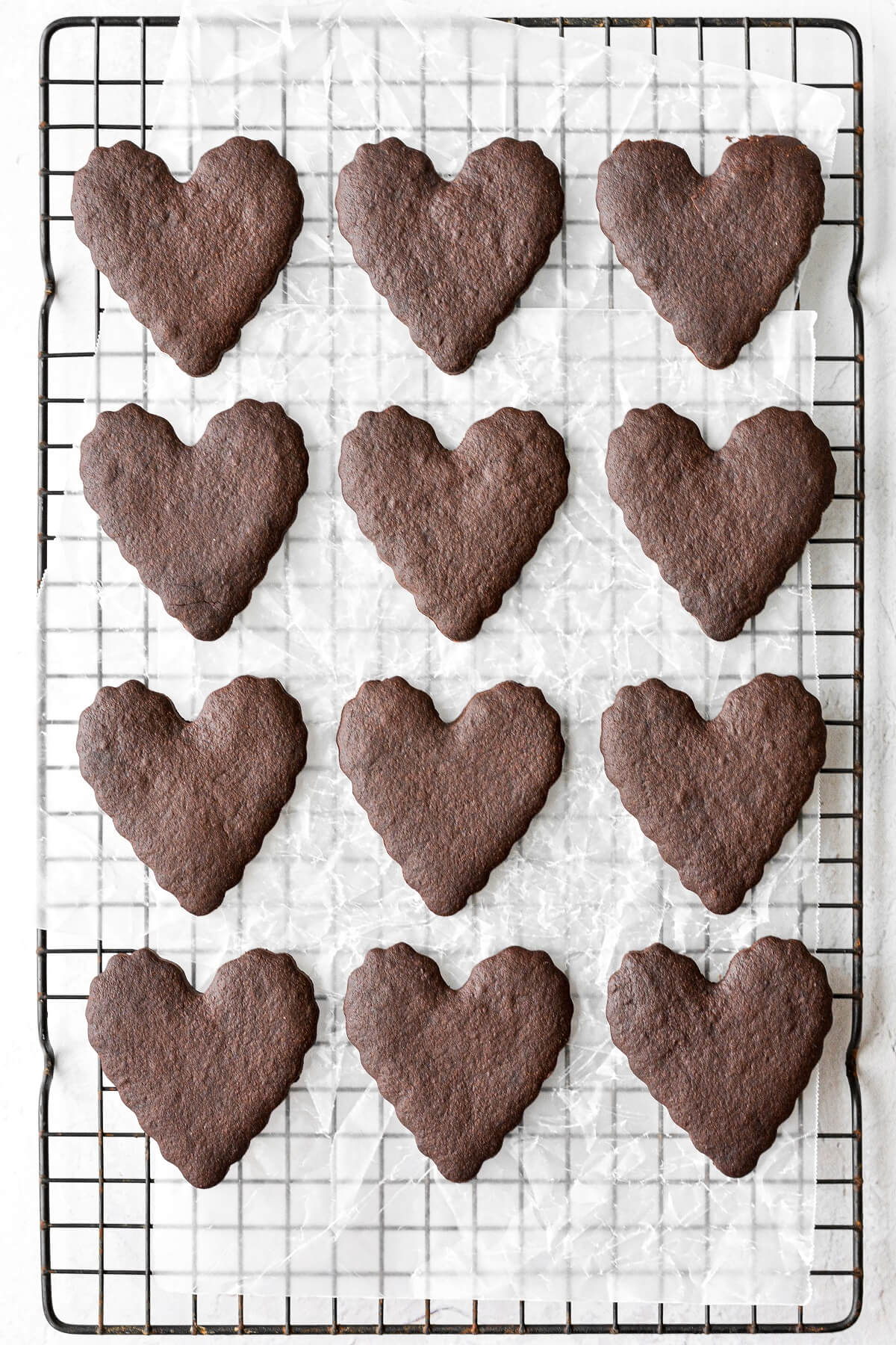 Heart shaped chocolate sugar cookies on a black cooling rack.