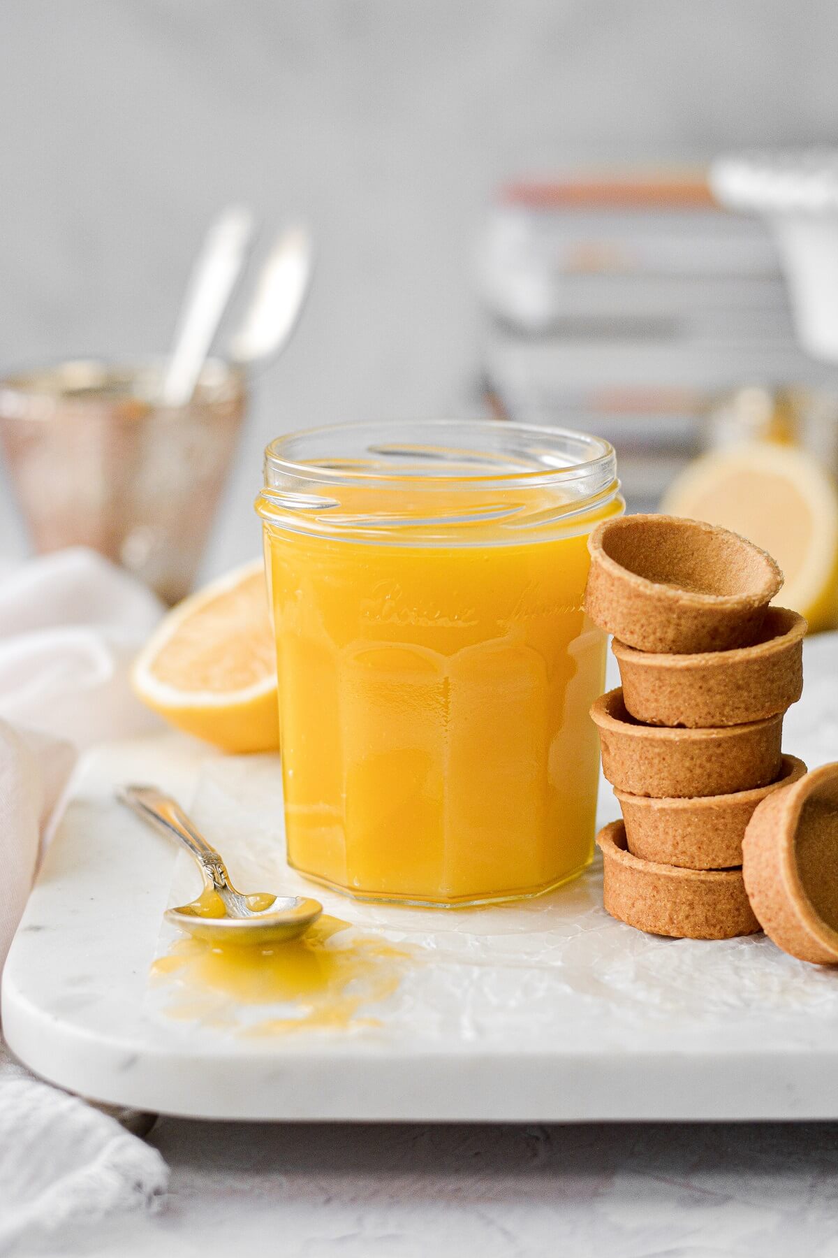 A jar of lemon curd, next to a stack of mini pastry shells.