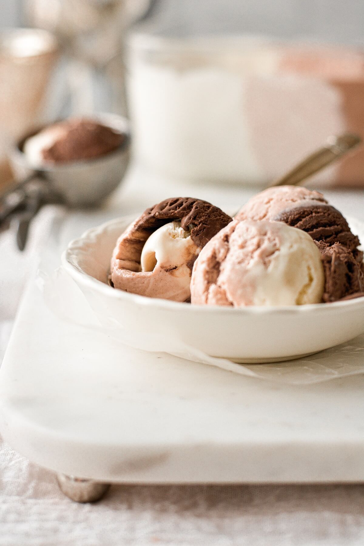 Three scoops of neapolitan ice cream in a white bowl.