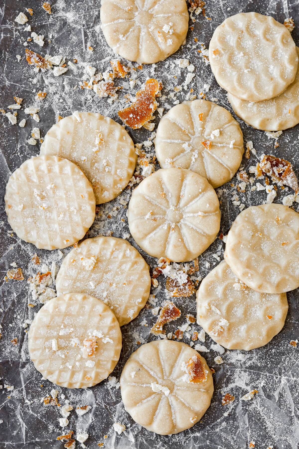 Ginger shortbread cookies with orange icing, scattered on a baking sheet.