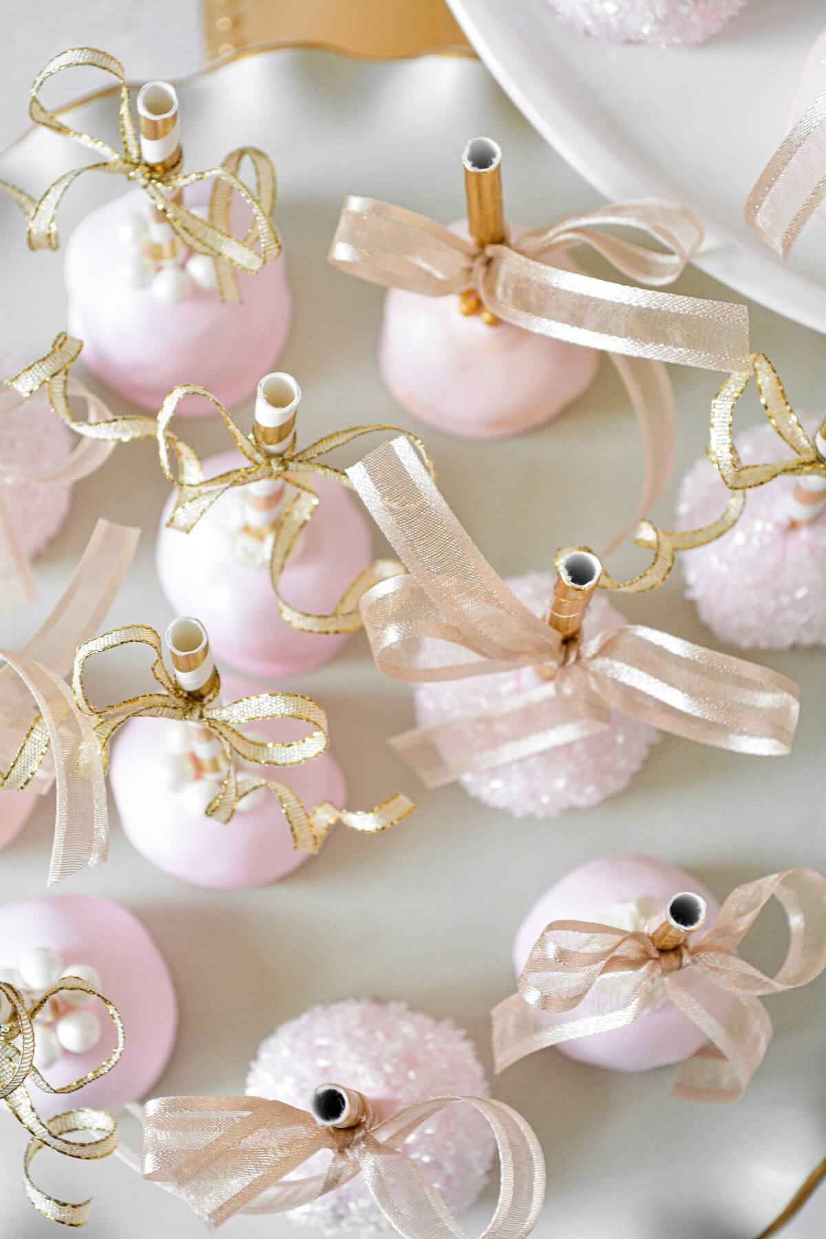 Pink and gold princess party cake pops with gold ribbons.