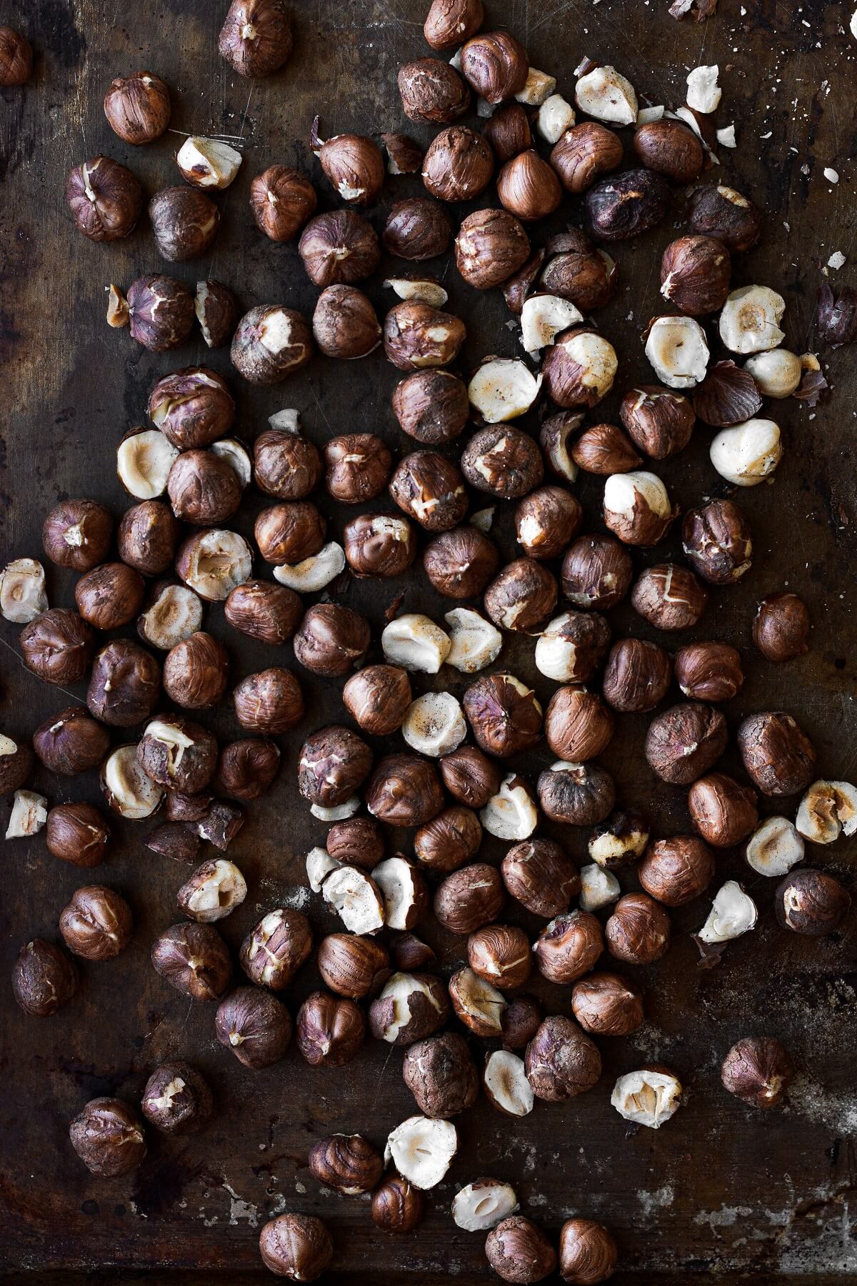 Toasted hazelnuts on a battered baking sheet.