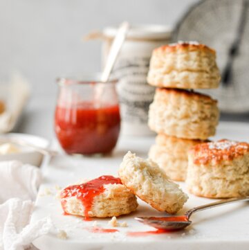 Baking powder biscuits on a marble serving board, with strawberry rhubarb jam.