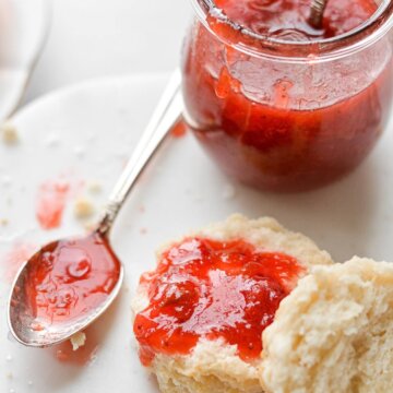 A biscuit split in half, topped with strawberry rhubarb jam.