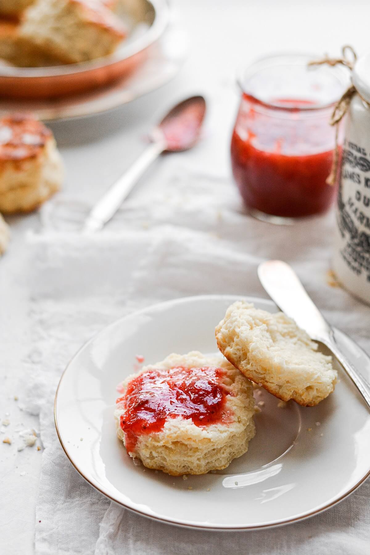 A baking powder biscuit split in half, topped with strawberry rhubarb jam.