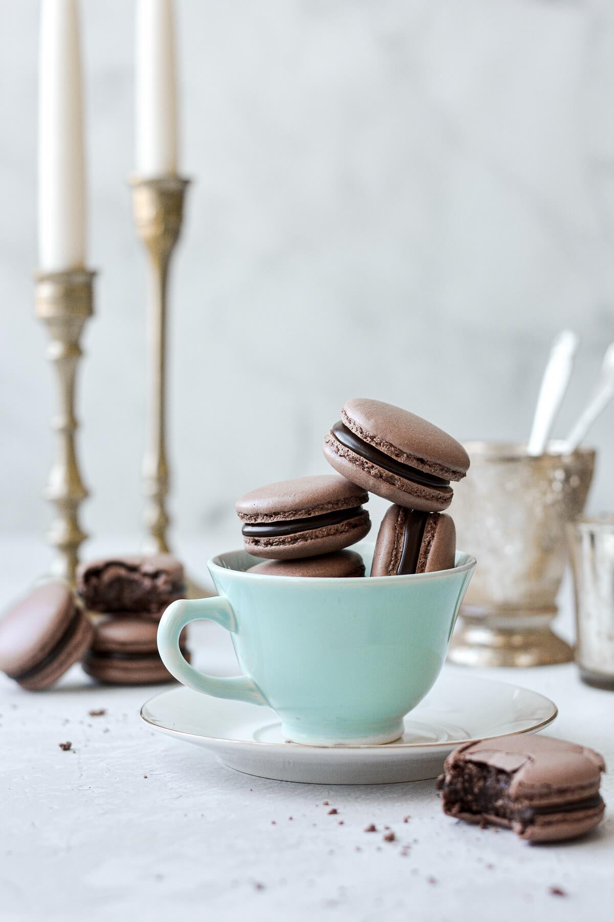 Chocolate macarons, filled with dark chocolate ganache, arranged in a vintage tea cup.