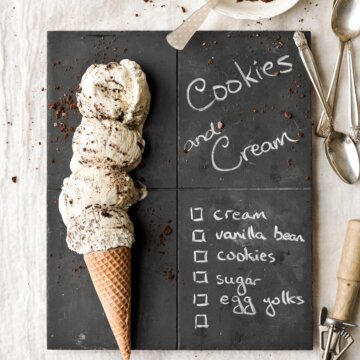 Scoops of cookies and cream ice cream on a chalkboard serving board.