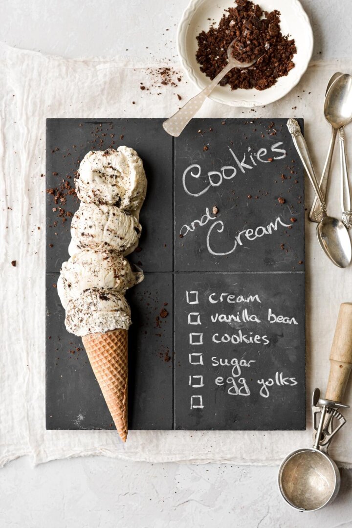 Scoops of cookies and cream ice cream on a chalkboard serving board.