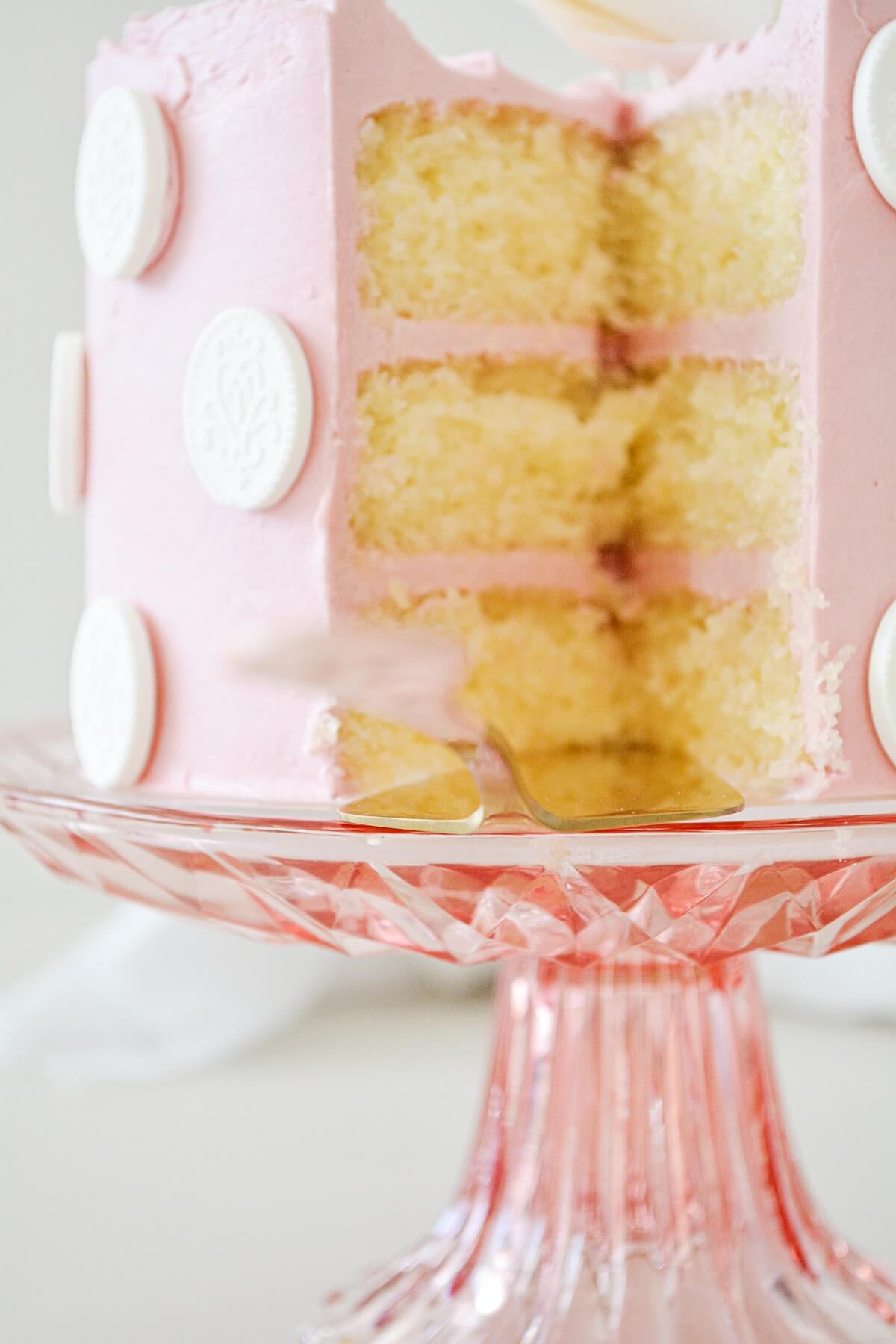 Lemon raspberry cake on a pink cake pedestal.