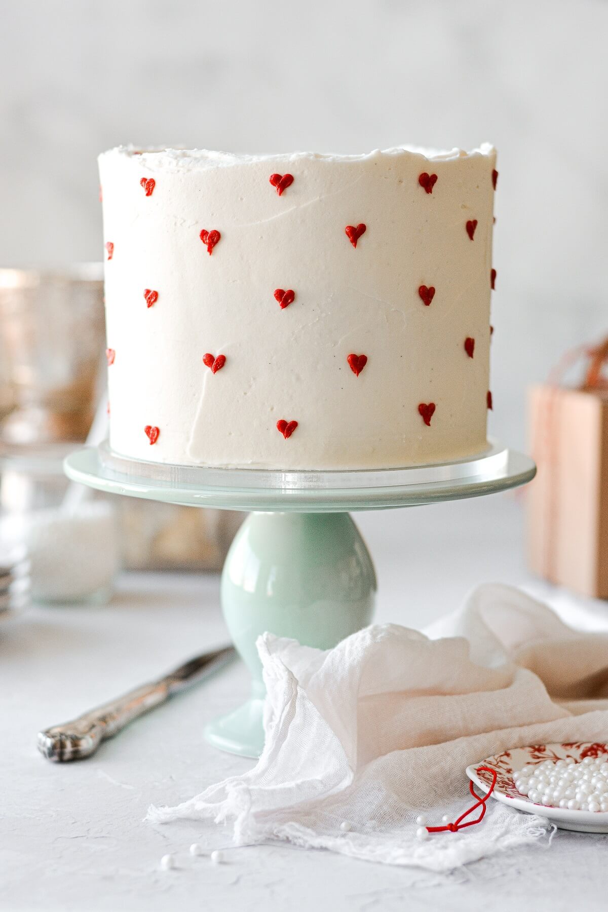 A Valentine's cake with red hearts piped onto white buttercream.
