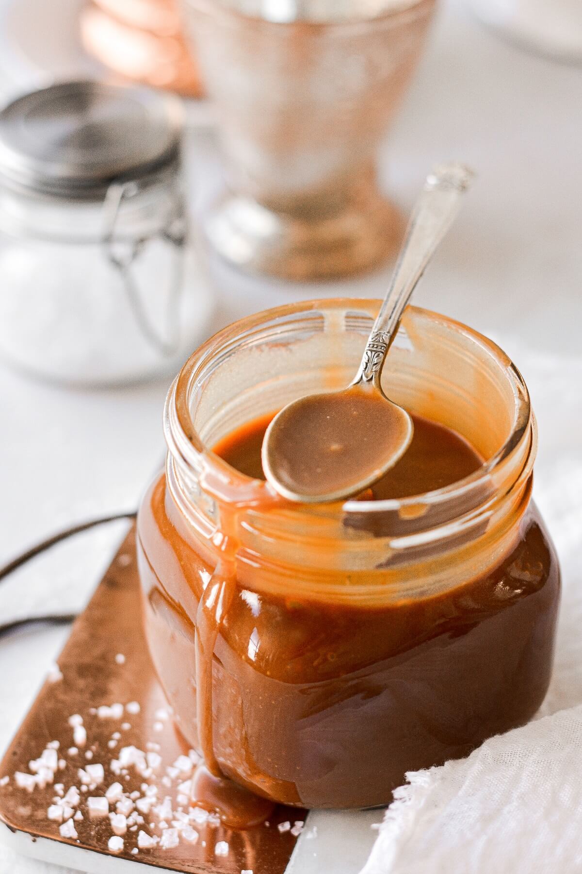 A jar of salted caramel sauce with a spoon resting on top.