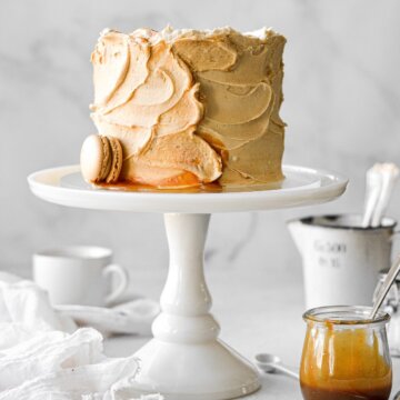 Caramel cake on a white cake pedestal.