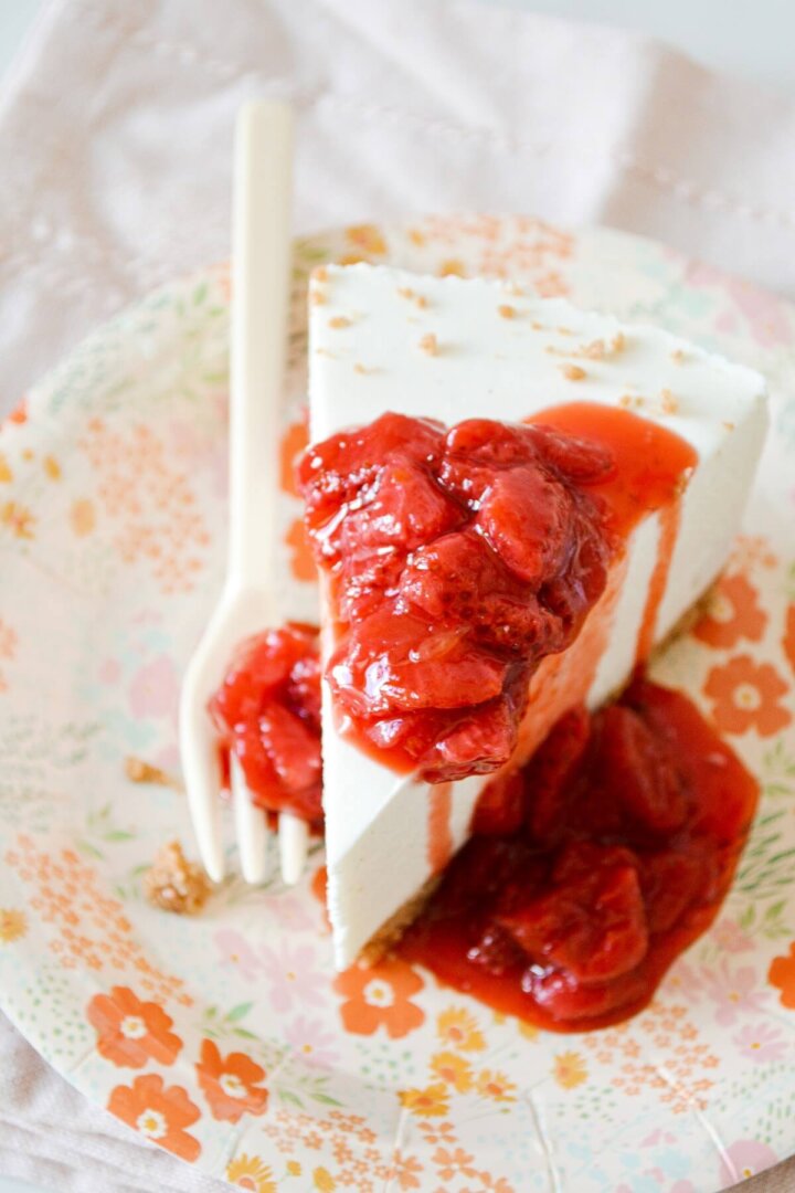 A slice of strawberry orange cheesecake with strawberry sauce.