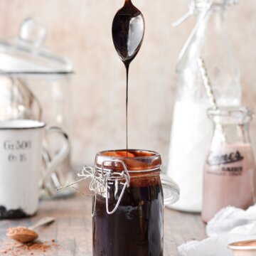 A spoonful of homemade chocolate syrup, drizzling into a jar of syrup..