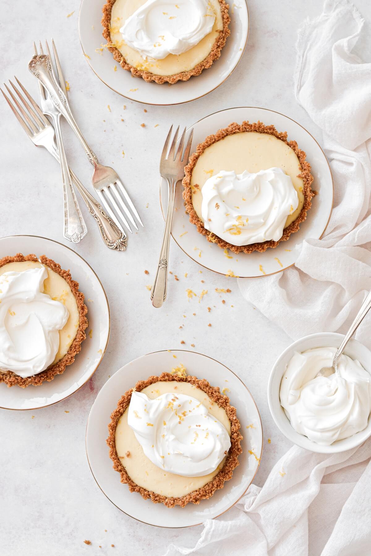 Lemon icebox pie, baked in individual lemon tarts, topped with whipped cream.