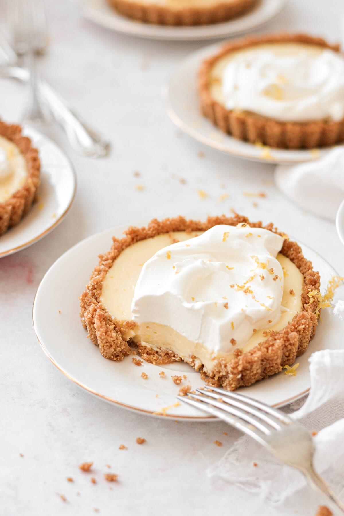 Lemon icebox pie, baked in individual lemon tarts, topped with whipped cream.