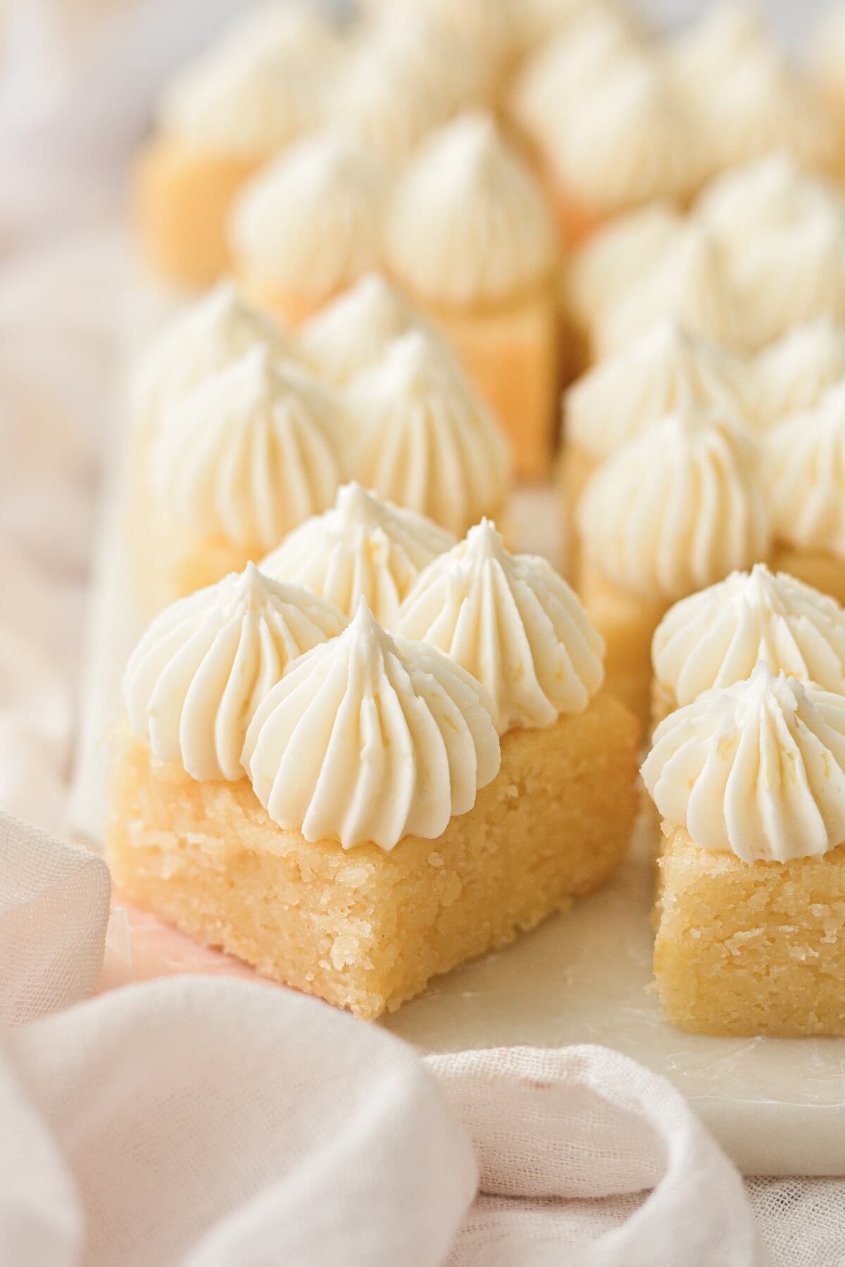 Lemonies, or lemon brownies, cut into squares and frosted with piped lemon buttercream.