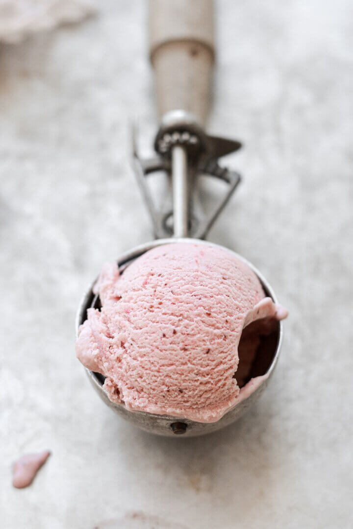 A scoop of roasted strawberry ice cream in a vintage ice cream scoop.