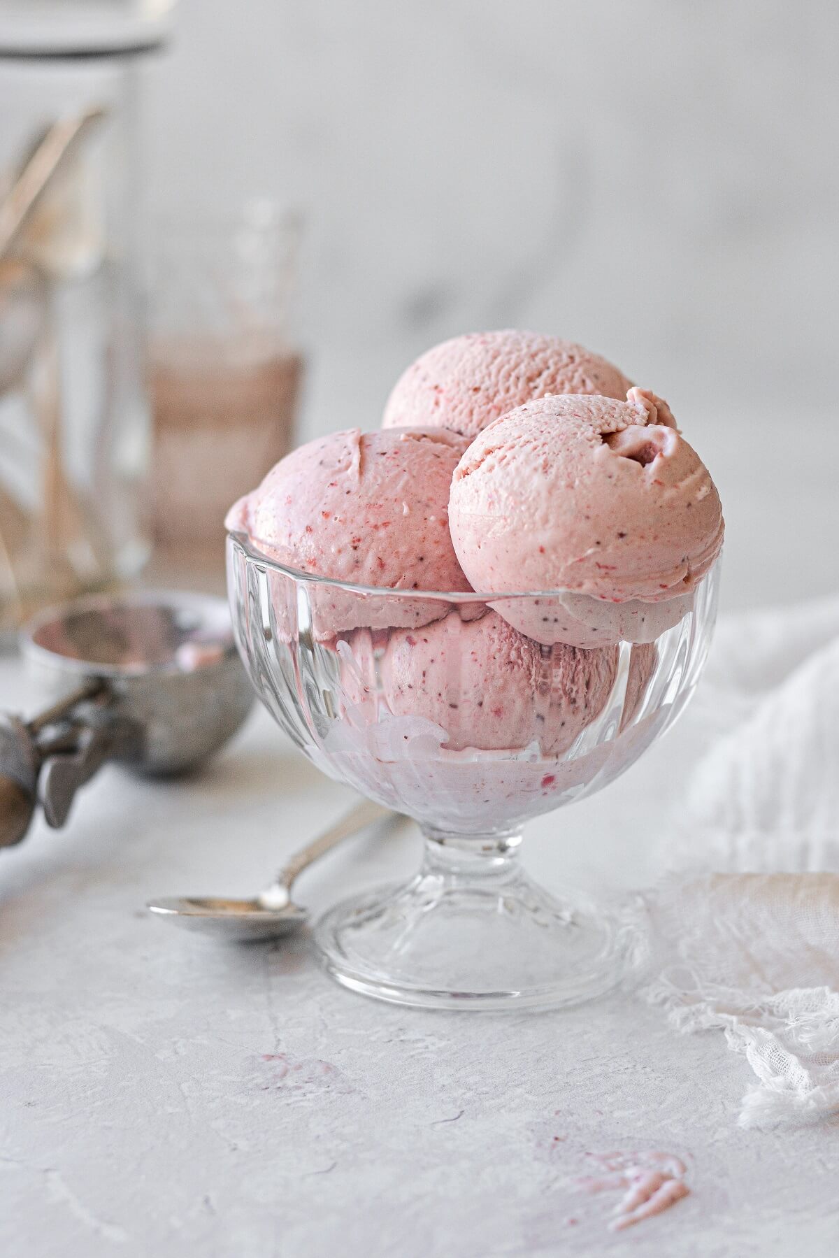 Scoops of roasted strawberry ice cream in a glass ice cream dish.