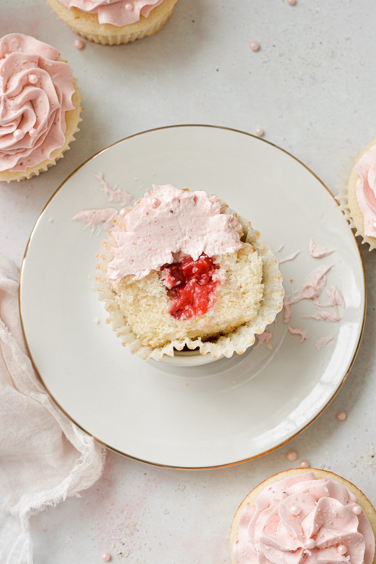 A strawberry cupcake cut in half to reveal the strawberry filling inside.