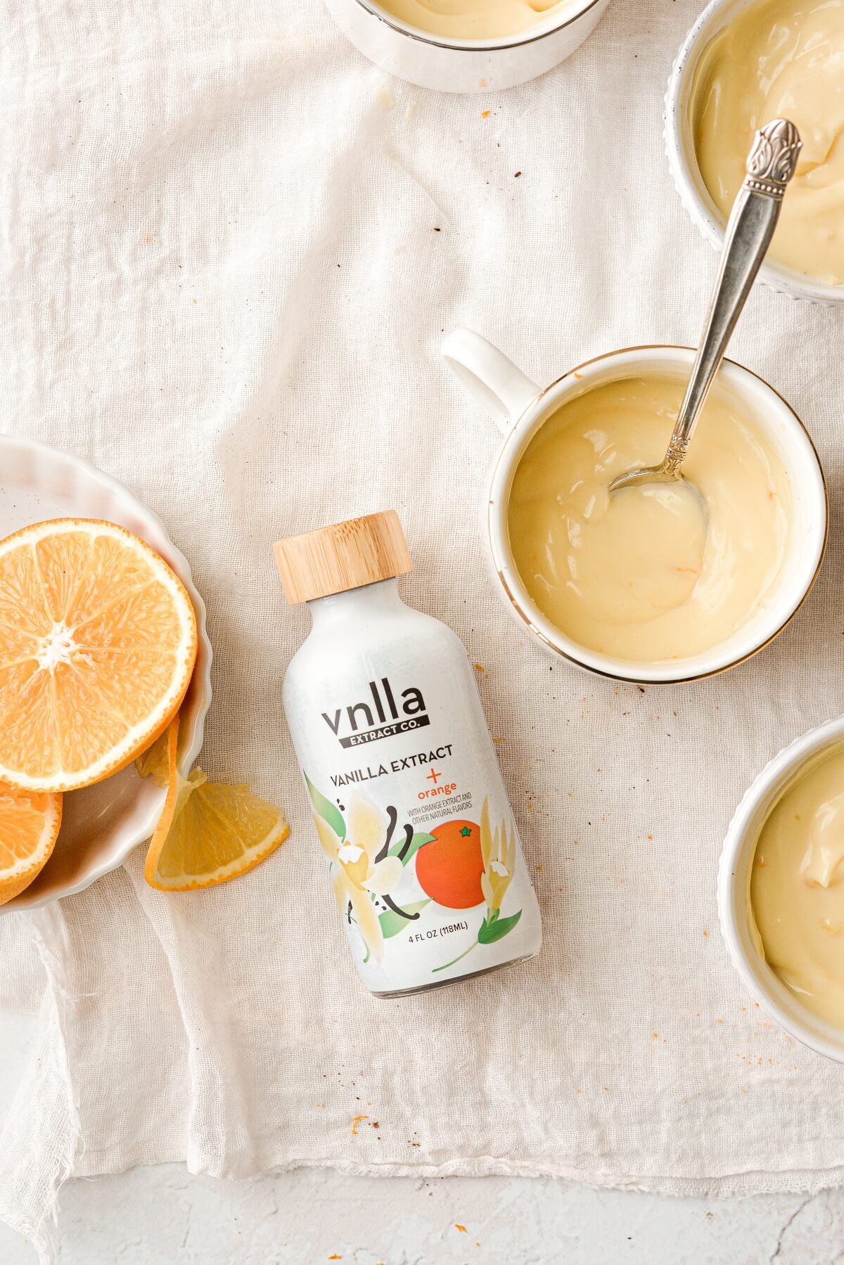 Ramekins of orange vanilla custard, with a bottle of vanilla extract from vnlla extract company.