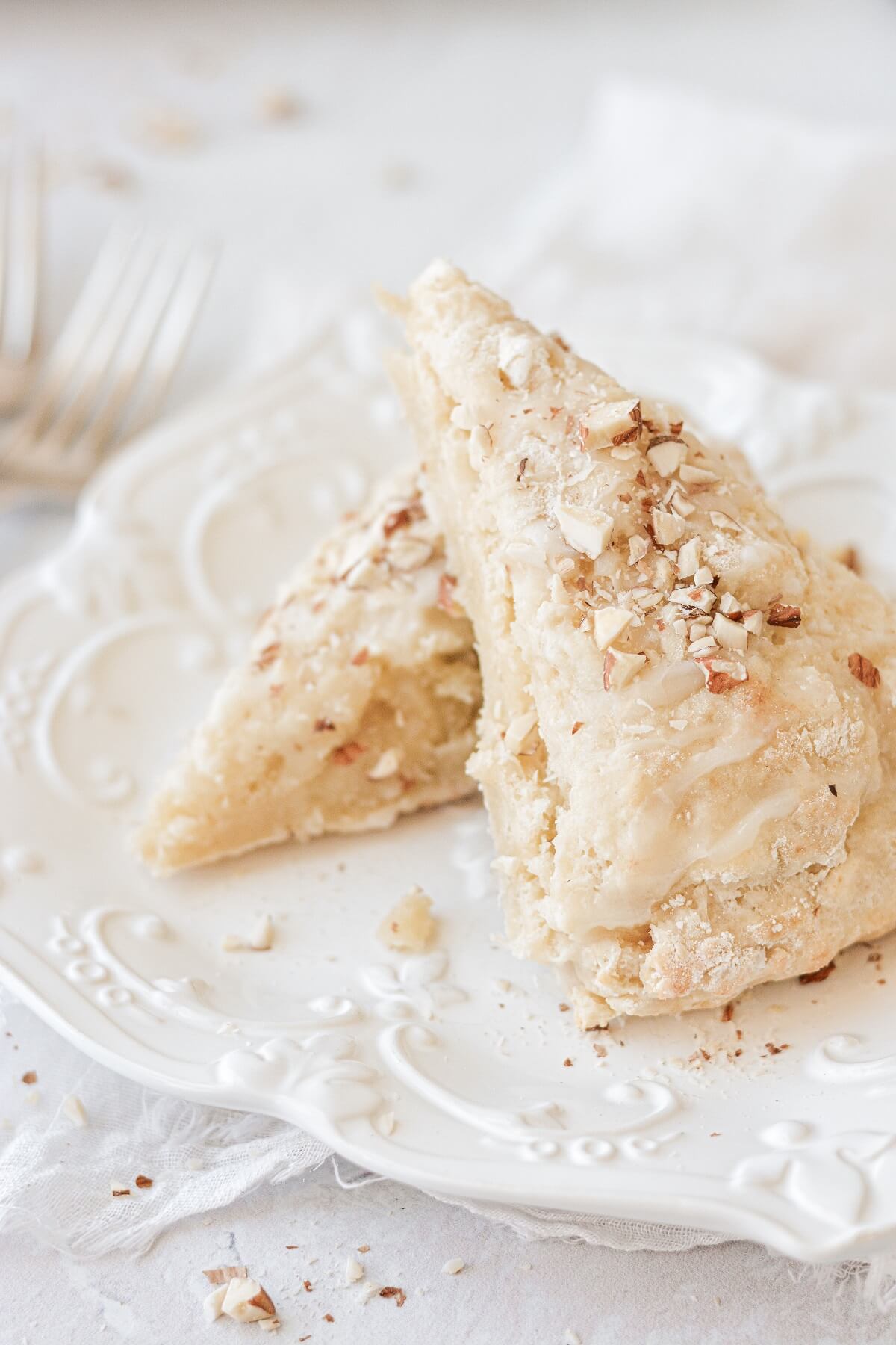 Almond cream cheese scones sprinkled with almonds, on a white plate.