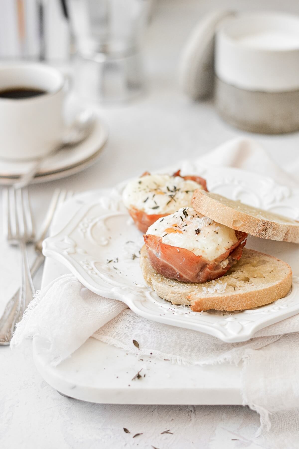 Baked prosciutto egg cups, sprinkled with thyme and parmesan, served with toast.