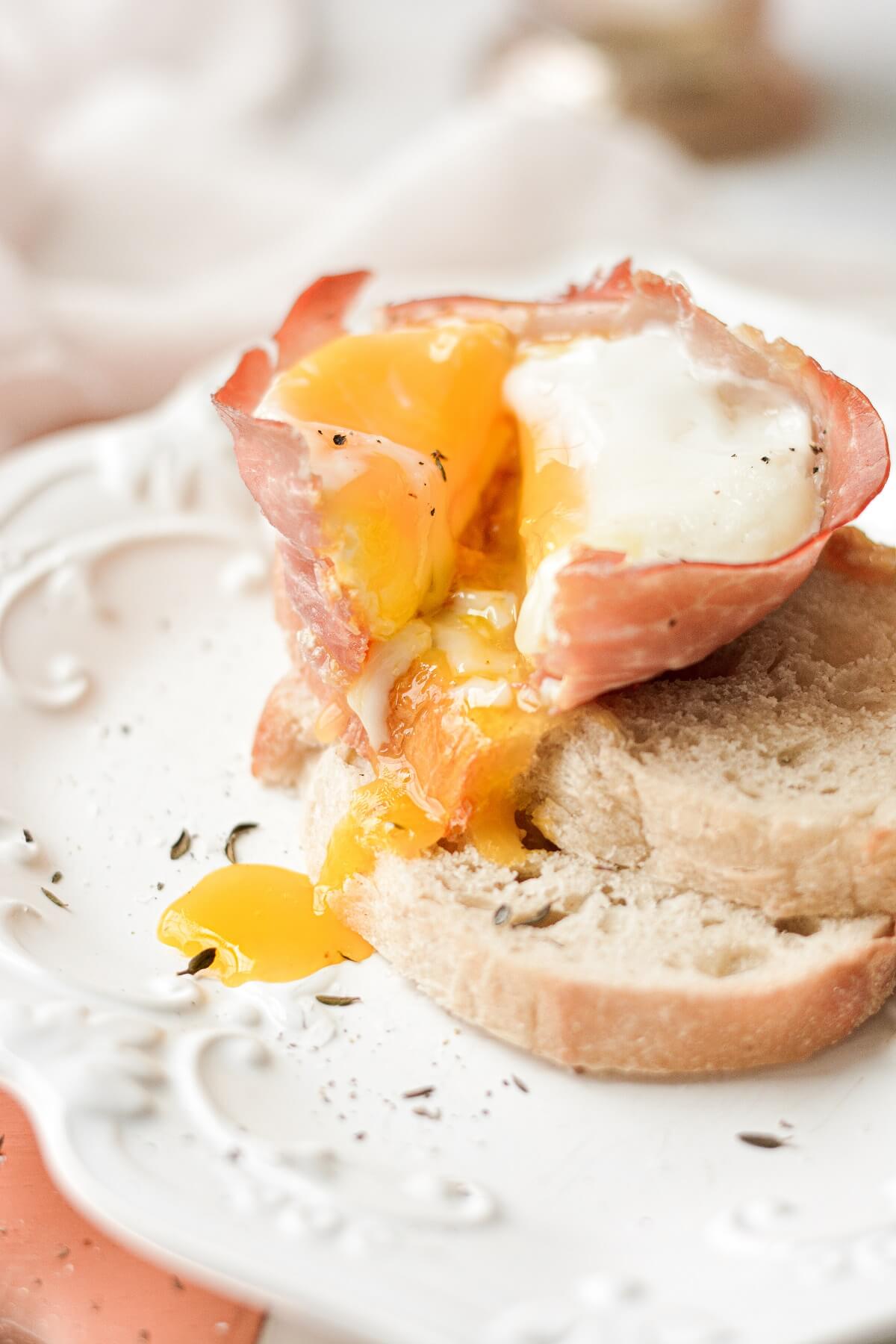 Baked prosciutto egg cups, sprinkled with thyme and parmesan, served with toast.
