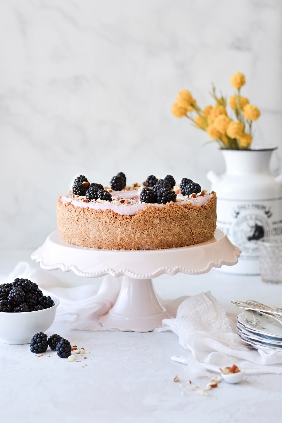 No bake blackberry cheesecake on a pink cake pedestal.