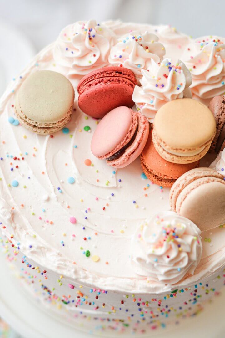 Funfetti cake topped with sprinkles and French macarons.