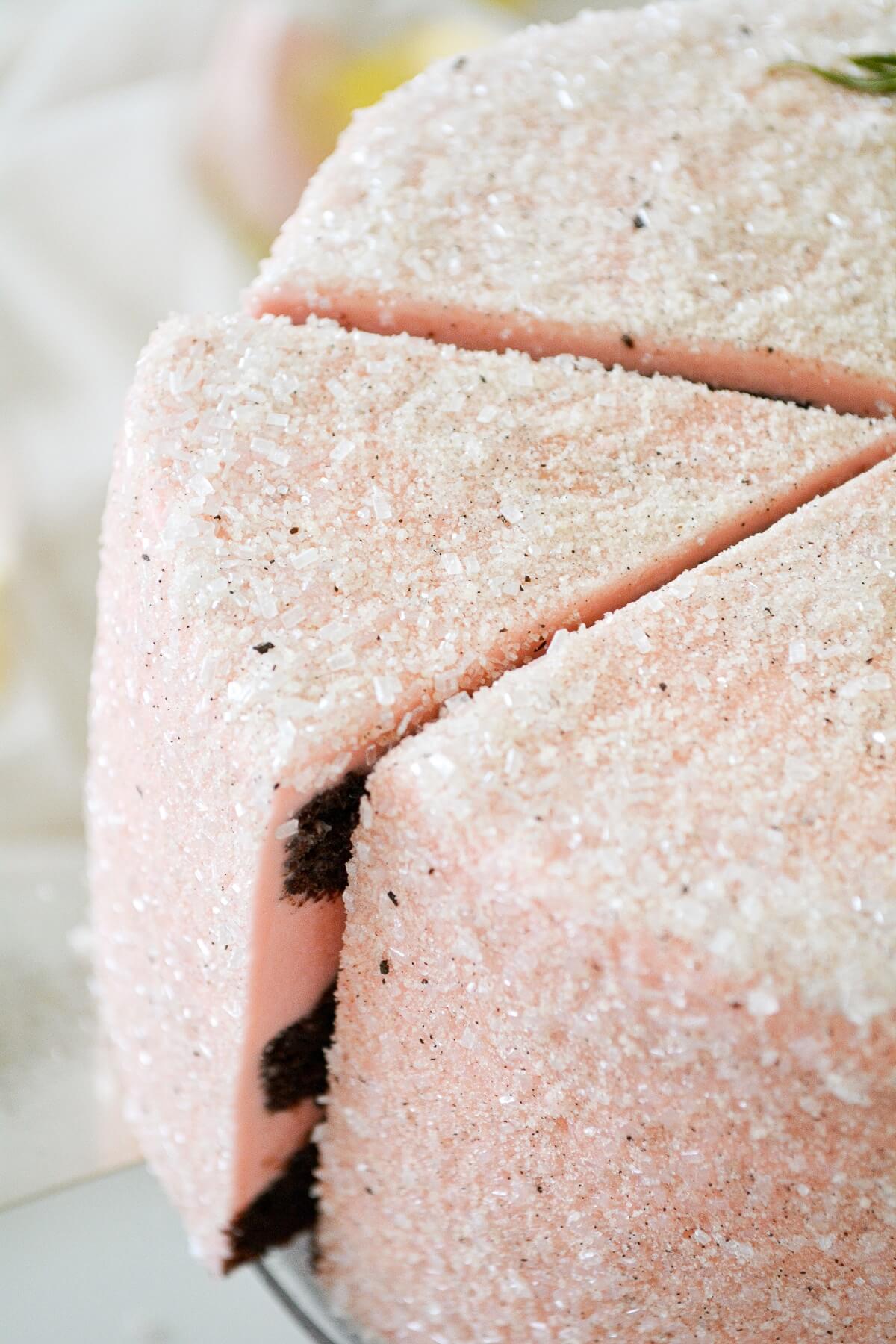 A slice of cake being lifted from a cake covered in sparkling sugar.