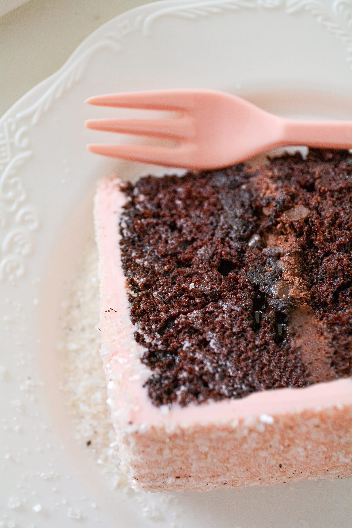 A slice of chocolate cake with chocolate filling and pink peppermint buttercream.