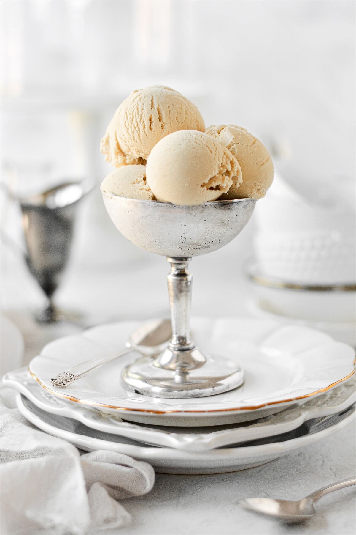 Scoops of brown sugar ice cream in a silver footed bowl.